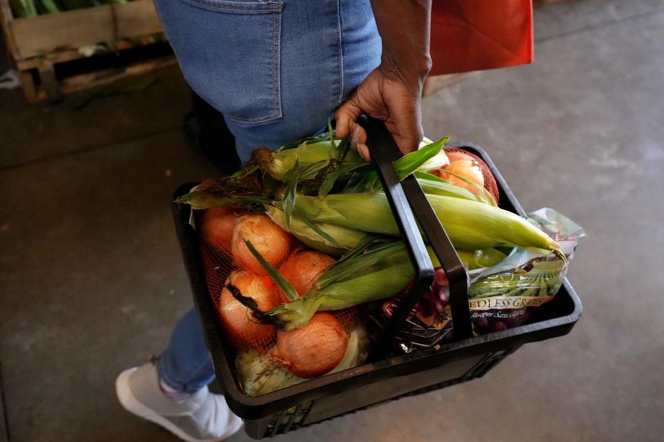 A shopper carries her produce June 8 at All People's Fresh Market, which exclusively serves fresh fruits, vegetables and dairy products.