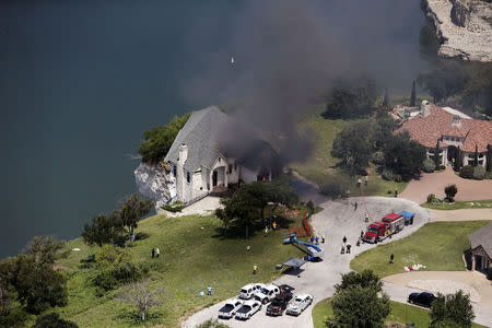 Smoke rises from a house deliberately set on fire, days after part of the ground it was resting on collapsed into Lake Whitney, Texas June 13, 2014. REUTERS/Brandon Wade