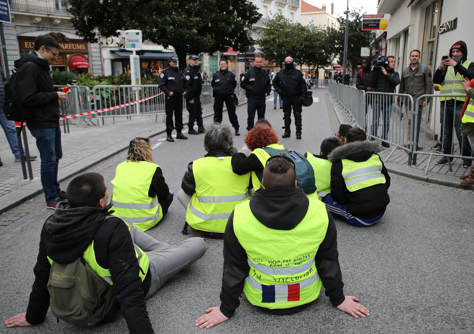 Demonstrators wearing yellow vests face riot police officers during a visit by French Foreign Minister Jean-Yves Le Drian in Biarritz, southwestern France, Tuesday, Dec. 18, 2018. Yellow vest protesters occupied dozens of traffic roundabouts across France even as their movement for economic justice appeared to be losing momentum on the fifth straight weekend of protests. (AP Photo/Bob Edme)