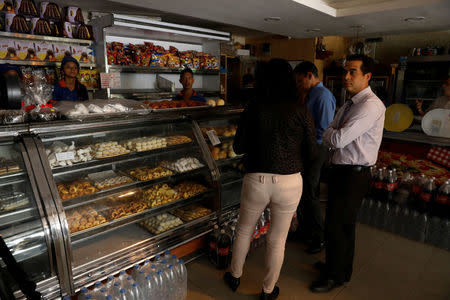 Customers wait in darkness inside a bakery, during a massive blackout in Caracas, Venezuela December 18, 2017. REUTERS/Marco Bello
