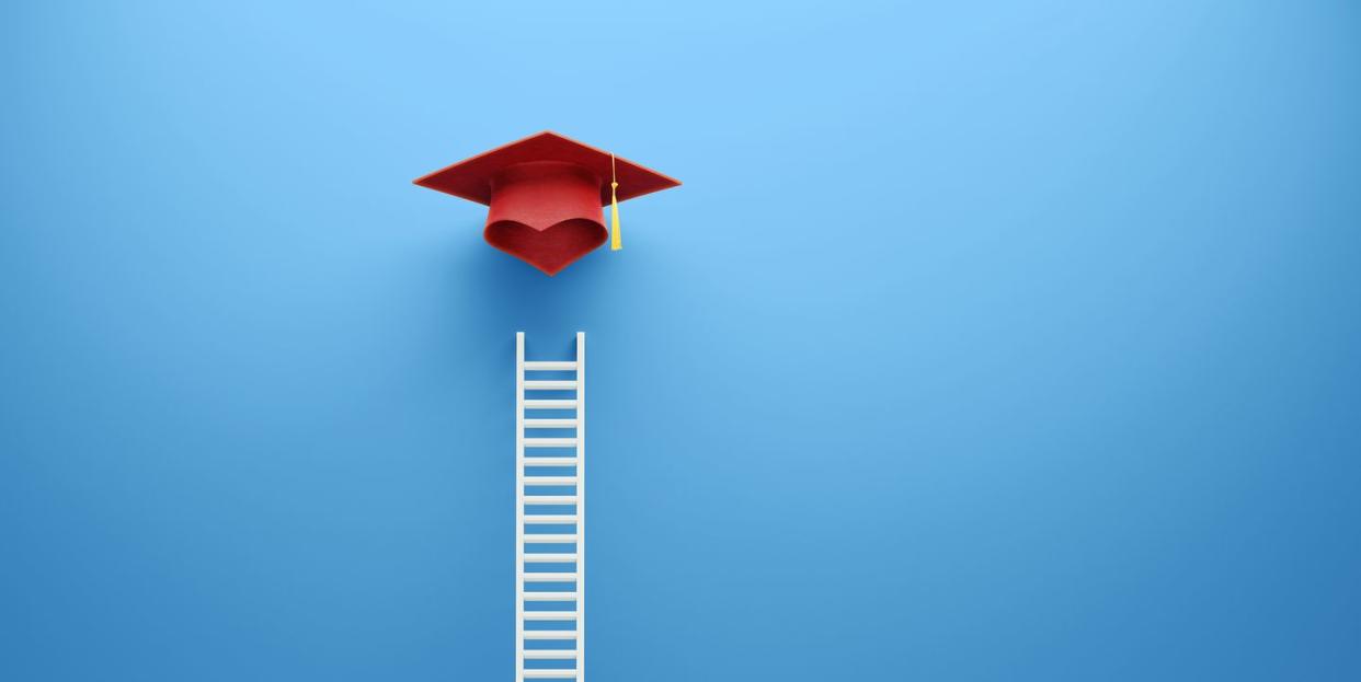 white ladder and red graduation cap leaning on blue wall