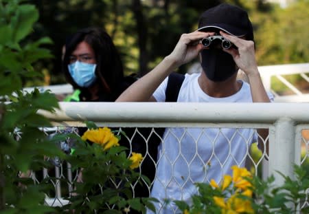 An anti-government protester looks though binoculars during a demonstration in Kowloon