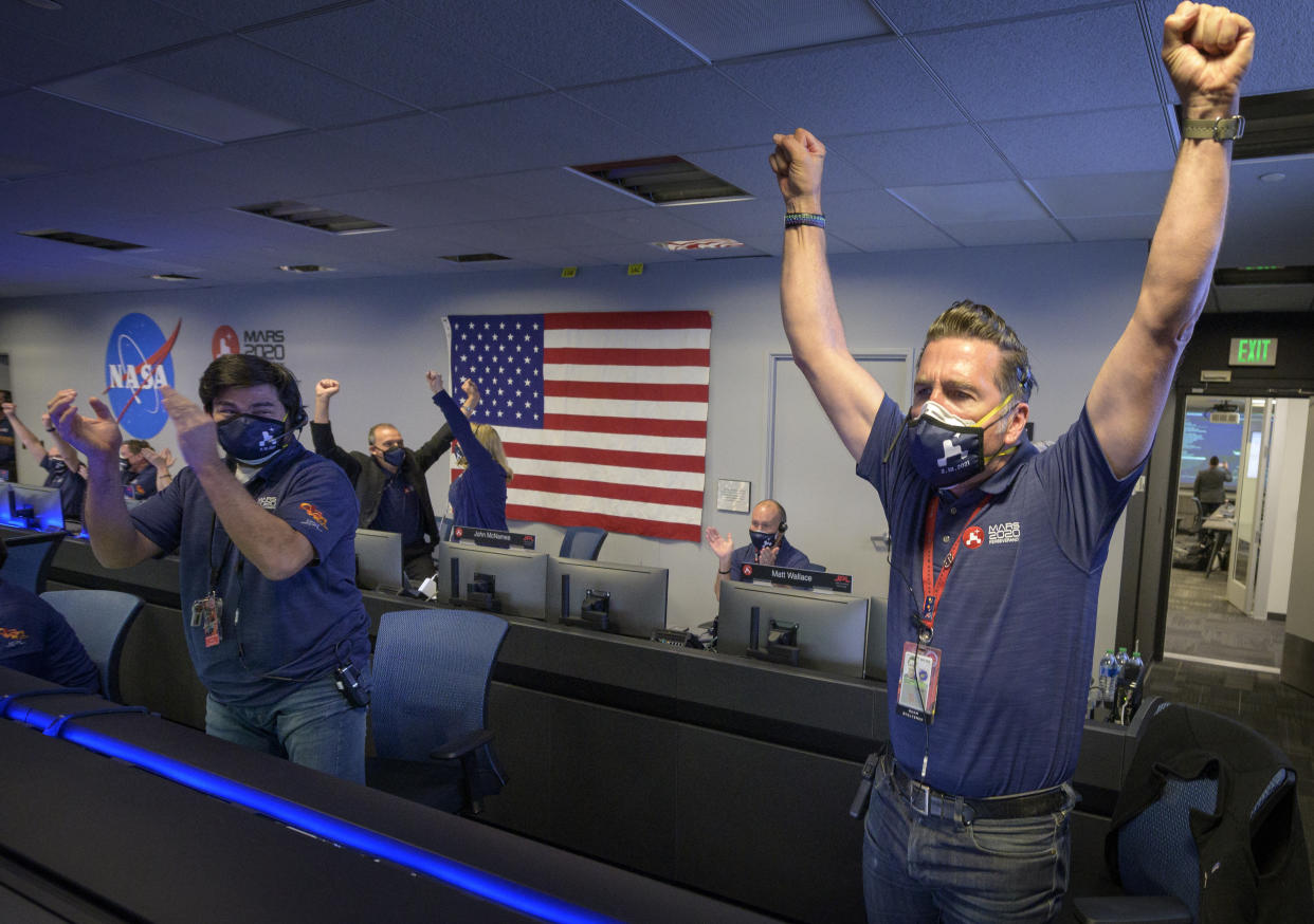 In this photo provided by NASA, members of NASA's Perseverance rover team react in mission control after receiving confirmation the spacecraft successfully touched down on Mars, Thursday, Feb. 18, 2021, at NASA's Jet Propulsion Laboratory in Pasadena, Calif. The landing of the six-wheeled vehicle marks the third visit to Mars in just over a week. Two spacecraft from the United Arab Emirates and China swung into orbit around the planet on successive days last week. (Bill Ingalls/NASA via AP)