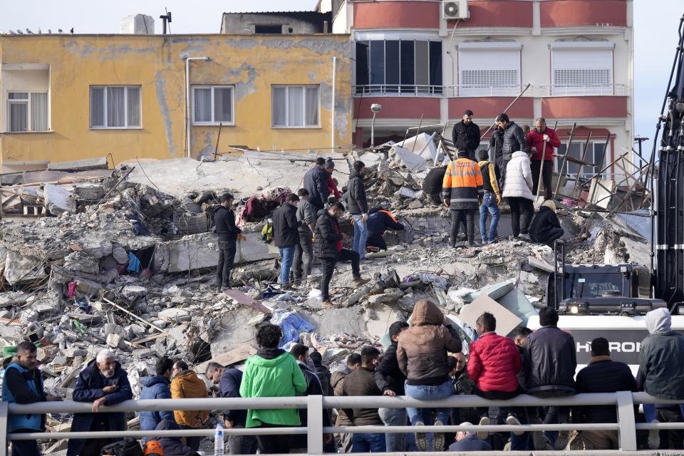 People and emergency teams search for survivors in the rubble of a destroyed building, in Iskenderun town, southern Turkey, Tuesday, Feb. 7, 2023. Ever since the powerful 7.8 earthquake that has become Turkey's deadliest disaster in modern history, survivors have been gathering outside destroyed buildings, refusing to leave. (AP Photo/Hussein Malla)