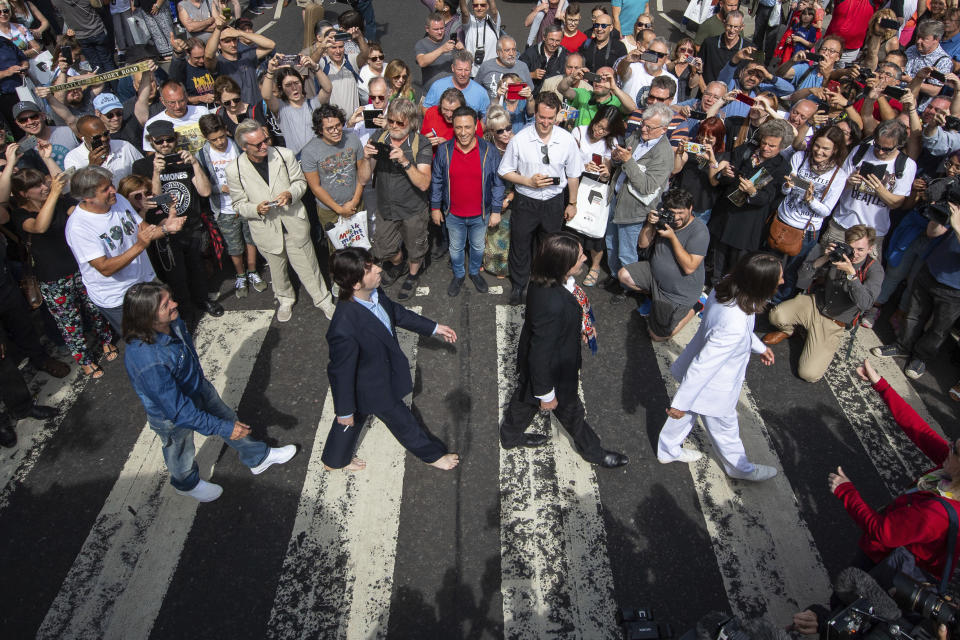 Thousands of fans gather to walk across the Abbey Road zebra crossing, on the 50th anniversary of British pop musicians The Beatles doing it for the cover of their album 'Abbey Road' in St Johns Wood in London, Thursday, Aug. 8, 2019. They aimed to cross 50 years to the minute since the 'Fab Four' were photographed for the album.(Dominic Lipinski/PA via AP)