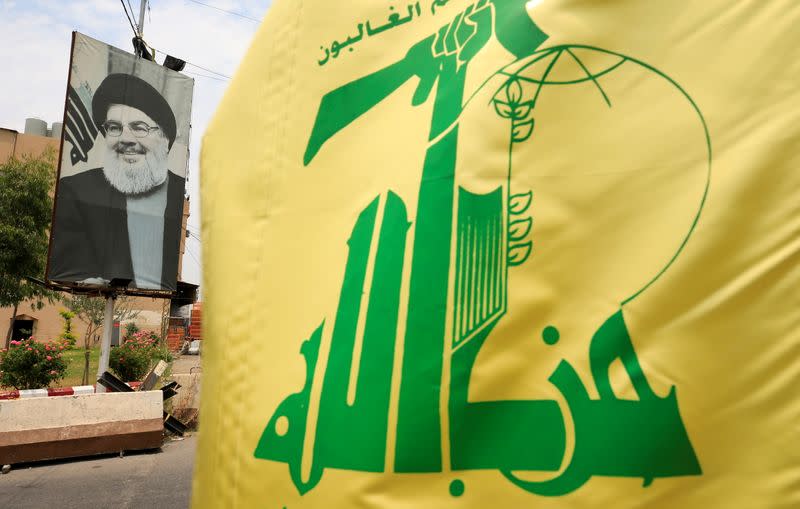 FILE PHOTO: A Hezbollah flag and a poster depicting Lebanon's Hezbollah leader Sayyed Hassan Nasrallah are pictured along a street, near Sidon