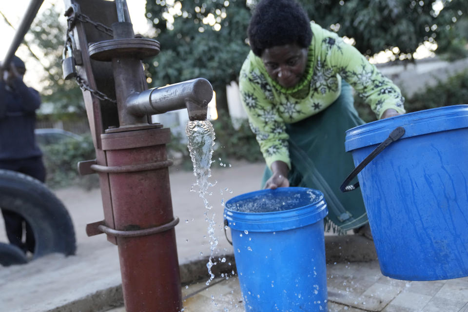 Jeffrey Carlos, left, helps his wife Christwish fetch water in Mabvuku on the outskirts of Harare on Wednesday, Aug, 3, 2022. Carlos, a father of three, says he gets about $100 dollars a month from his job as an overnight security guard for a church and the bar next door. Rising prices and a fast-depreciating currency have pushed many Zimbabweans to the brink, reminding people of when the southern African country faced world-record inflation of 5 billion % in 2008.(AP Photo/Tsvangirayi Mukwazhi)