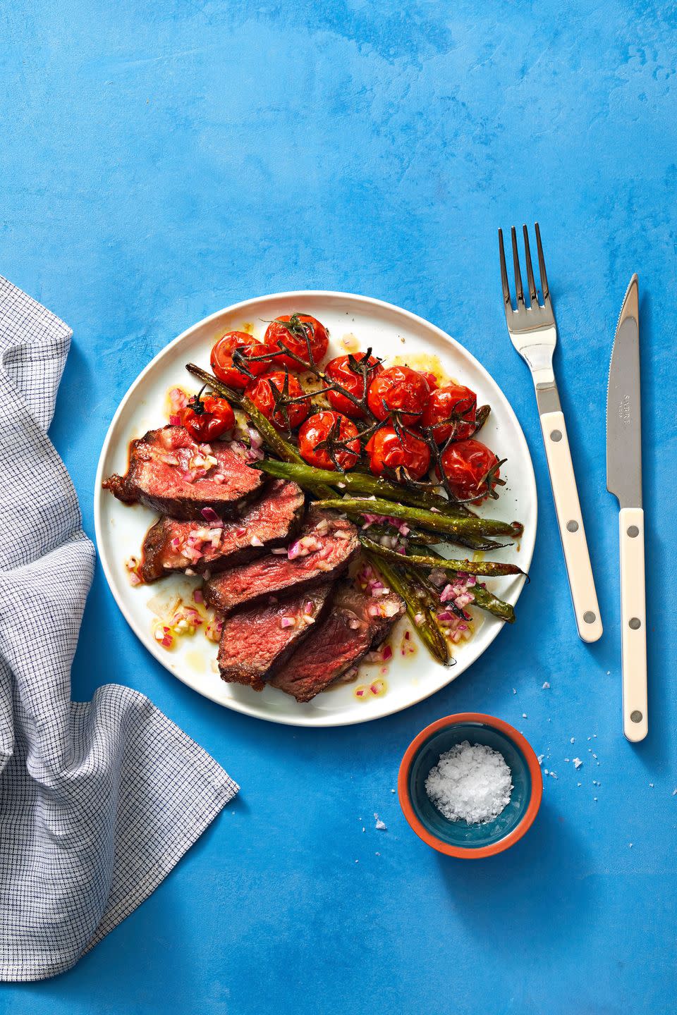 steak, asparagus, and tomatoes on a white plate