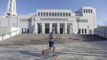 A jogger runs past The Church of Jesus Christ of Latter-day Saints' Conference Center during the 190th Annual General Conference Saturday, April 4, 2020, in Salt Lake City. The twice-annual conference kicked off Saturday without anyone attending in person and top leaders sitting some 6 feet apart inside an empty room viewed via live-stream as the faith takes precautions to avoid the spread of the coronavirus. It is the first conference without a crowd since World War II, when wartime travel restrictions were in place. (AP Photo/Rick Bowmer)