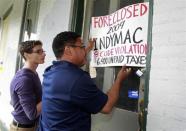 Drew Gibson (L) and Robert Pace of Occupy Cincinnati and Occupy the Hood hang a signs with the names of banks involved in the foreclosure of a home during a march in Cincinnati, Ohio March 24, 2012. Occupy activists across America say they have found a cause that represents an issue for the "99 percent" and embodies the movement's anti-Wall Street message: helping struggling homeowners fight foreclosure and eviction. Picture taken March 24, 2012.