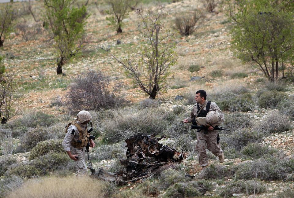 Lebanese army soldiers from a commando unit check the remains of a bomb-packed vehicle after they blew it up a in a field outside the village of Fakiha, near the Lebanese and Syria border, in northeast Lebanon, Monday, March 17, 2014. Lebanese commandos combed the tense border areas between Lebanon and Syria early Monday shortly after troops discovered and denoted an SUV rigged with explosives. The Lebanese army is searching for rebels crossing into the country after their last stronghold on the other side of the frontier fell into Syrian government hands on Sunday.(AP Photo/Hussein Malla)