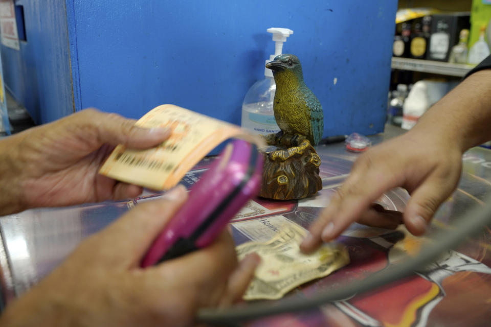 People buy multiple lottery tickets for the Powerball lottery at the Blue Bird Liquor store in Hawthorne, Calif., Monday, Oct. 31, 2022. The jackpot for Monday night's drawing soared after no one matched all six numbers in Saturday night's drawing. It's the fifth-largest lottery jackpot in U.S. history. (AP Photo/Damian Dovarganes)