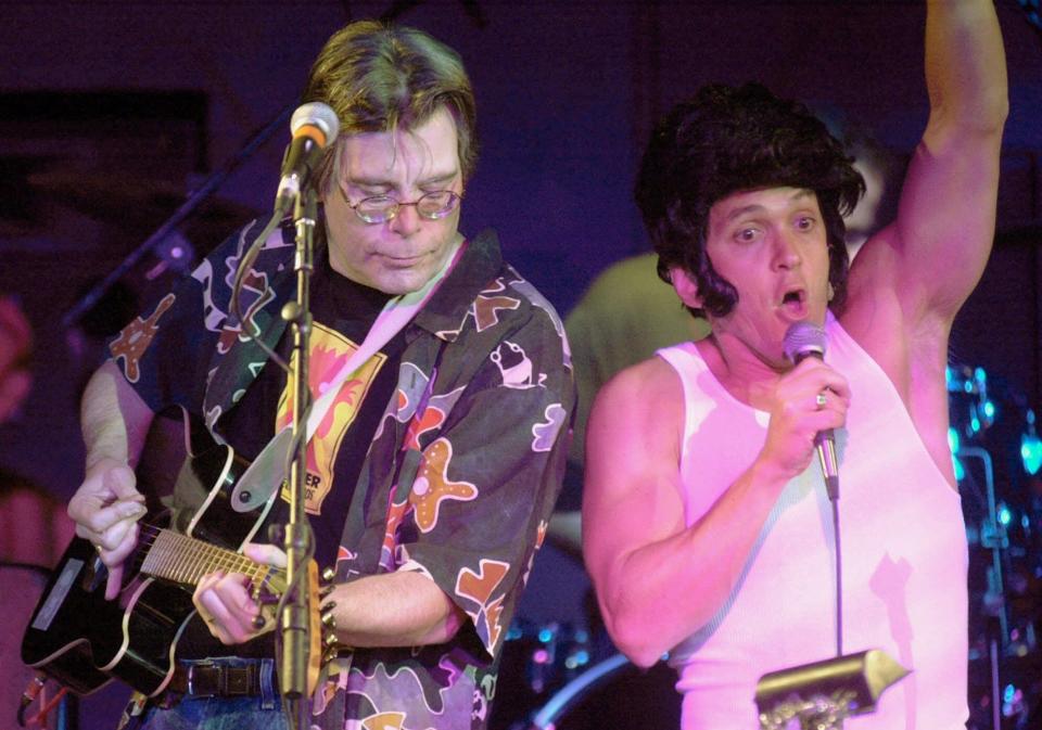 Author Stephen King, left, plays guitar as fellow writer Mitch Albom, wearing an Elvis hairdo, sings with the band Rock Bottom Remainders at a benefit performance in Boston on Nov. 16, 2000. The band's members are mostly writers and also has included Amy Tan, Dave Barry and Ridley Pearson.