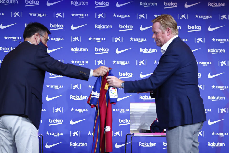 Ronald Koeman, right is handed a Barcelona soccer shirt by club Director Josep Bartome during his official presentation as coach for FC Barcelona in Barcelona, Spain, Wednesday, Aug. 19, 2020. Barcelona officially announced earlier on Wednesday a deal with Koeman to become their coach five days after the team's humiliating 8-2 loss to Bayern Munich in the Champions League quarterfinals. Barcelona says the former defender's deal runs through June 2022. Koeman replaces the fired Quique Setien. (AP Photo/Joan Monfort)
