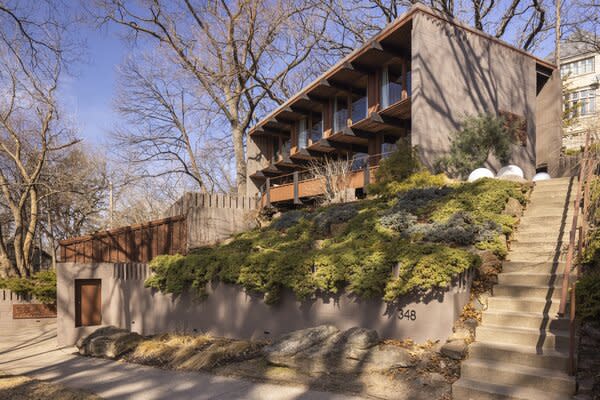 Concrete stairs lead up to the multi-level residence, perched atop a large, tree-filled lot.