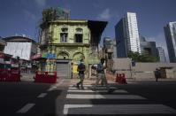 People cross a road as they return to work in the morning in Colombo, Sri Lanka, Monday, June 21, 2021. Sri Lanka eased a nearly one month-long travel ban on Monday, despite requests by the leading medical experts no to do so. The government said the lockdown style-travel ban will be lifted for three days, but only two persons from each family are allowed to go out. The travel ban was imposed on May 21 after the third wave of the COVID-19 erupted in April. (AP Photo/Eranga Jayawardena)