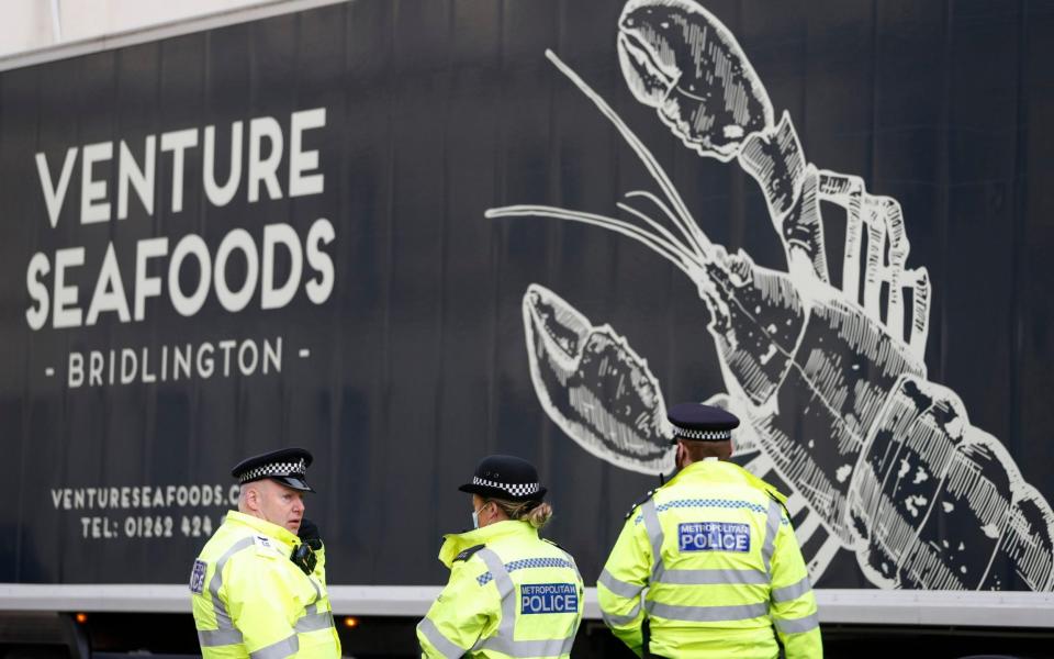 Police speak to a shellfish export truck driver as he is stopped for an unnecessary journey - AP