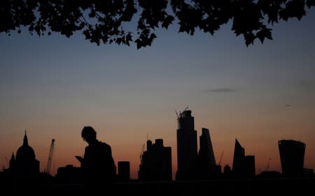 FILE PHOTO: A man walks past the city of London financial district as dawn breaks in London