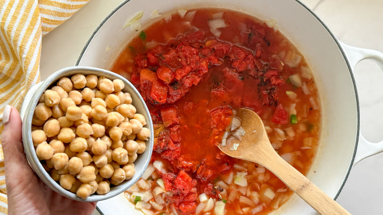 adding chickpeas to tomato soup pot