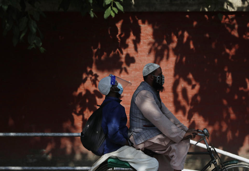 Nepalese men wearing face masks ride on a bicycle in Kathmandu, Nepal, Wednesday, May 5, 2021. Authorities extended lockdown in the capital Kathmandu and surrounding districts by another week on Wednesday as the Himalayan nation recorded the highest COVID-19 daily infection and death. (AP Photo/Niranjan Shrestha)