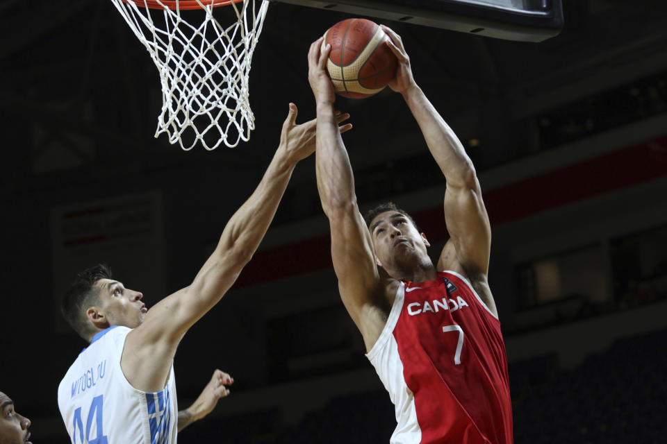 Canada's Dwight Powell drives to the hoop as Greece's Konstantinos Mitoglou tries to defend during the first half of a FIBA men's Olympic qualifying basketball game Tuesday, June 29, 2021 at Memorial Arena in Victoria, British Columbia. (Chad Hipolito/The Canadian Press via AP)