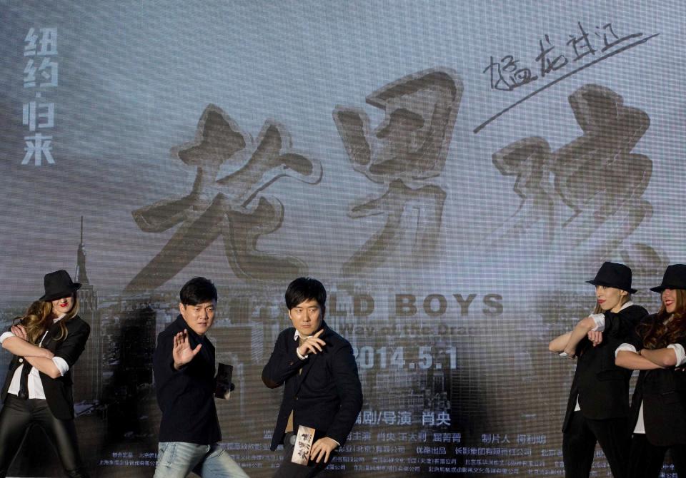 Chinese film director and actor Xiao Yang, second from left, and actor Wang Taili, center, pose with the dancers on stage as they promote their new movie “Old Boys: The Way of the Dragon” in Beijing Thursday, Jan. 9, 2014. An online microfilm that was watched by millions and helped to establish a genre in China is to be made into a feature-length movie and shown in the country’s cinemas. The planned debut of “Old Boys” in China’s cinemas in May after ratcheting up almost 70 million views on a video website demonstrates how online films are influencing the traditional film industry. (AP Photo/Andy Wong)