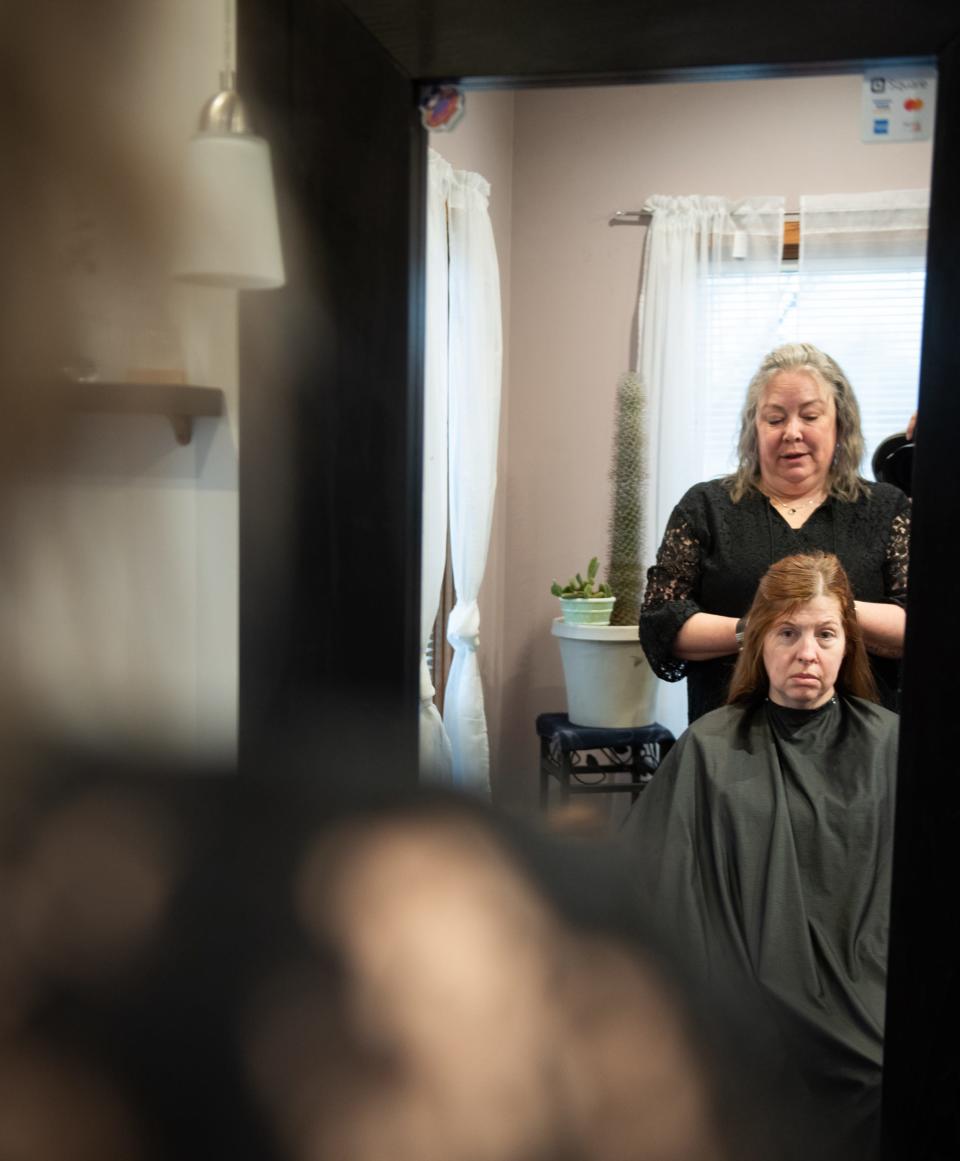 Stacy Balmes of Mason styles the hair of retired Ingham County Sheriff Det. Amber Kenny-Hinojosa on Thursday, March 14, 2024, at the salon where they first met in 2021. Kenny-Hinojosa interceded in Balmes' situation and days later Balmes' husband was arrested and charged with aggravated stalking. "She didn't know a thing about me, and in that one appointment she changed our lives," Balmes says.