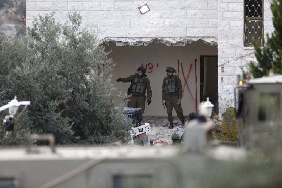 Israeli soldiers stand in a partially demolished house at the Shweikeh village near the West Bank city of Tulkarem, Monday, Dec. 17, 2018. The Israeli military has partially demolished the home of Ashraf Naalweh, a Palestinian accused of killing two Israelis in a West Bank attack two months ago. (AP Photo/Majdi Mohammed)