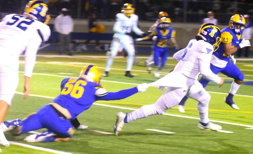 Dos Palos High School sophomore defensive lineman Justin Hurd (56) tries to bring down Exeter quarterback Jacob Molina (6) during a playoff game on Friday, Nov. 17, 2023.