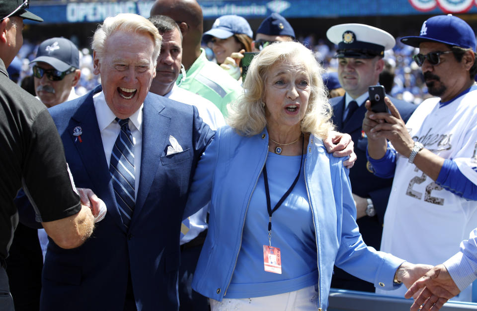 FILE - In this April 12, 2016, file photo, Los Angeles Dodgers broadcaster Vin Scully, left, with his wife, Sandra Scully, walk off the field after he was honored before the start of an opening day baseball game against the Arizona Diamondbacks in Los Angeles. The Los Angeles Dodgers say Sandra Scully died Sunday, Jan. 3, 2021, at age 76. She had been dealing with the neuromuscular disease ALS over the last several years and died at Ronald Reagan UCLA Medical Center in Los Angeles. She and Vin Scully celebrated their 47th wedding anniversary in 2020. (AP Photo/Alex Gallardo, File)