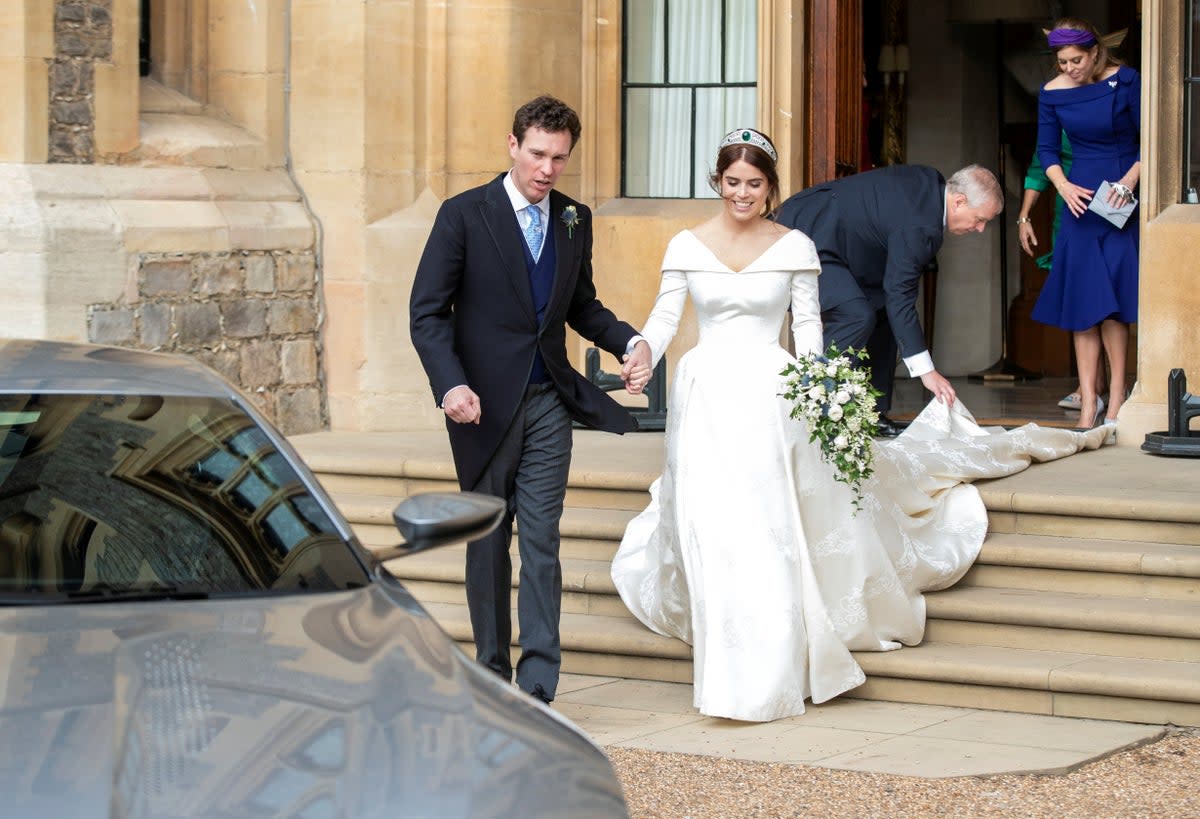 Princess Eugenie of York reacts as she and and her husband Jack Brooksbank walk to an Aston Martin DB10 as they leave Windsor Castle for Royal Lodge (AFP via Getty Images)