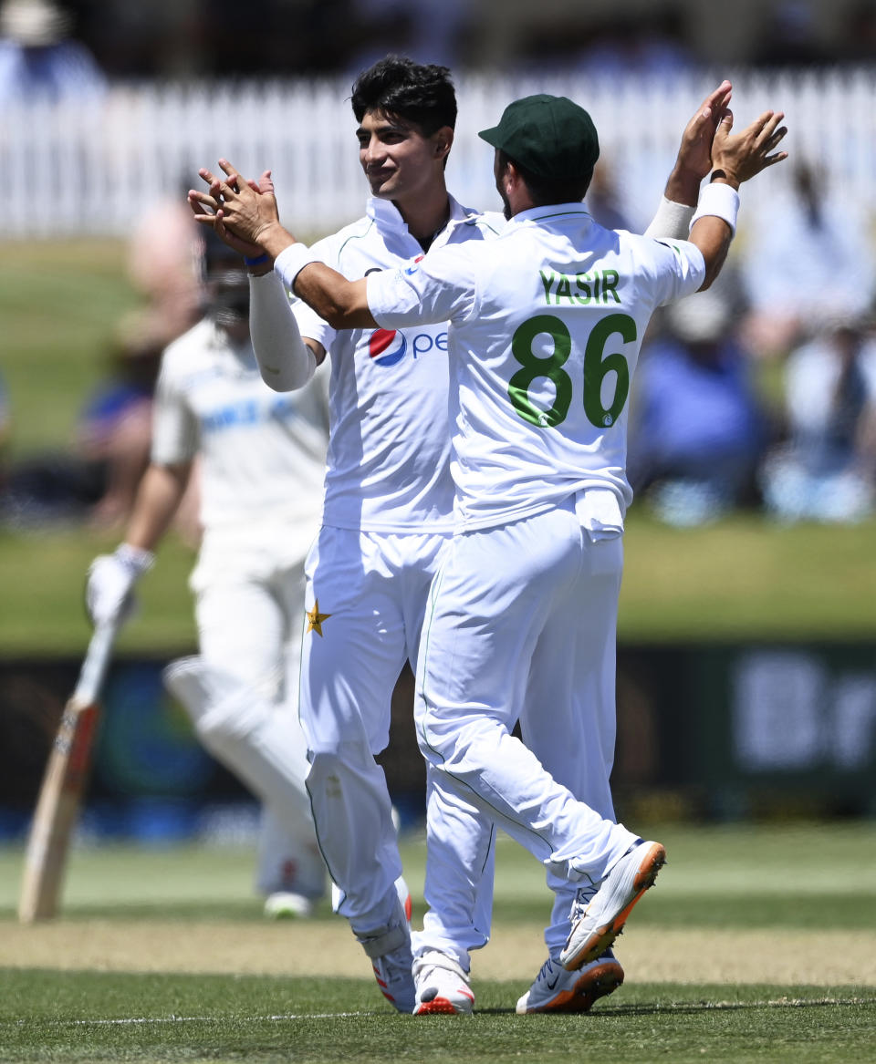 Pakistan bowler Naseem Shah, left, celebrates the wicket of Henry Nicholls during play on day two of the first cricket test between Pakistan and New Zealand at Bay Oval, Mount Maunganui, New Zealand, Sunday, Dec. 27, 2020. (Andrew Cornaga/Photosport via AP)