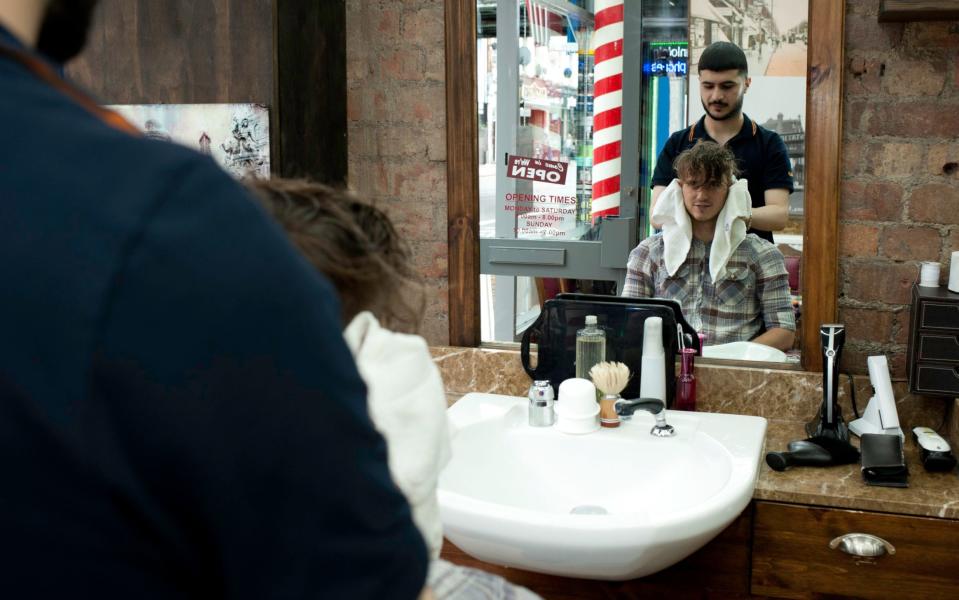 Mirror image of young man and barber in barber shop