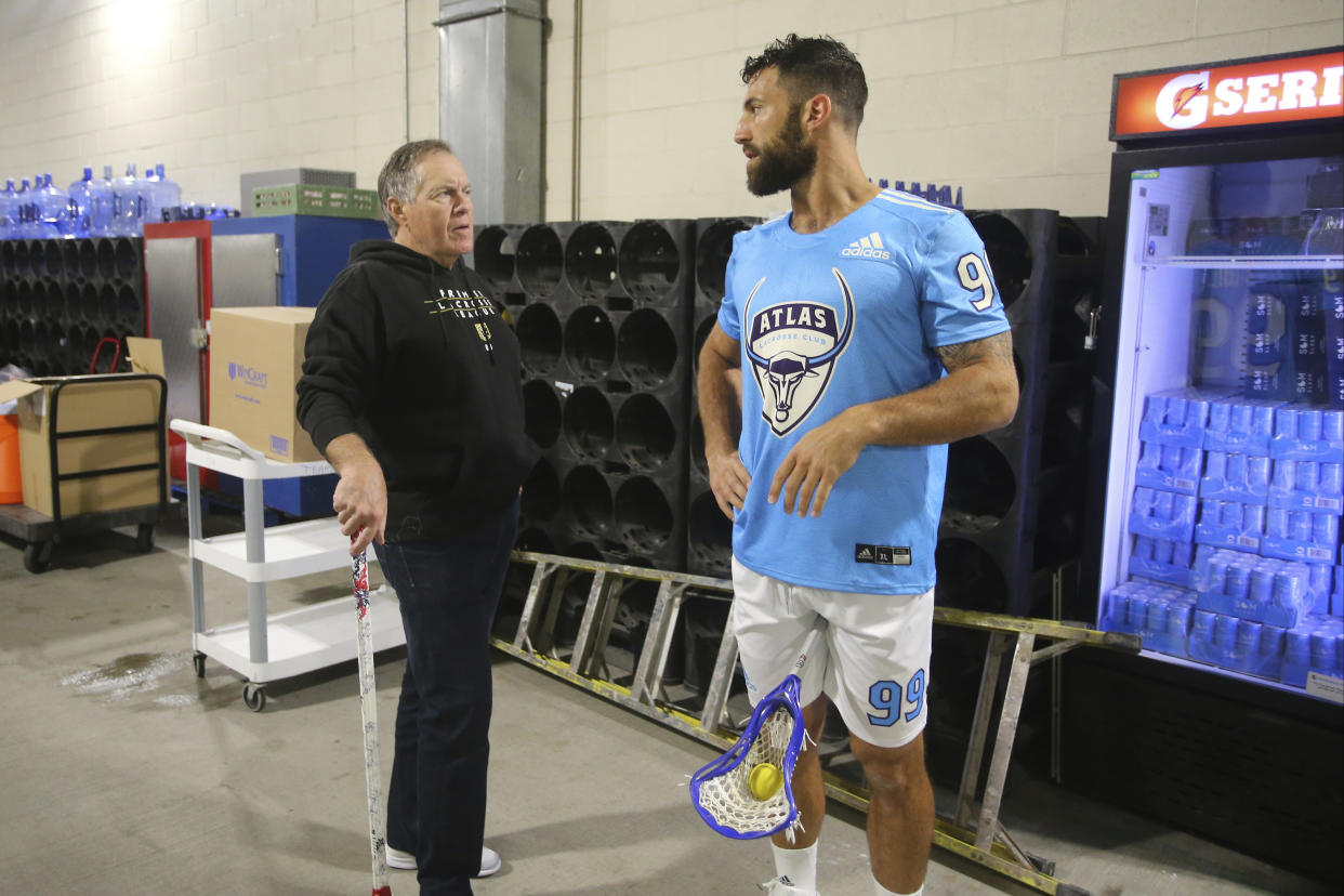 Bill Belichick holds a lacrosse stick while speaking with PLL co-founder Paul Rabil. (Stew Milne/AP Images for Premier Lacrosse League)