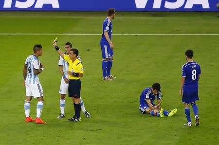 Argentina's Marcos Rojo (L) receives a yellow card by the referee Joel Aguilar as Bosnia's Mensur Mujdza (2nd R) reacts during their 2014 World Cup Group F soccer match at the Maracana stadium in Rio de Janeiro June 15, 2014. REUTERS/Ricardo Moraes