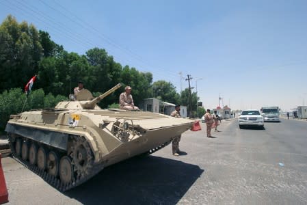 Iraqi soldiers sit on a tank at the entry of Zubair oilfield after a rocket struck the site of residential and operations headquarters of several oil companies in Basra