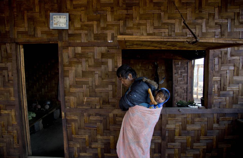 CORRECTS GENDER OF TSAW TSAW TO GIRL- In this Jan. 28 2014 photo, Hpatau Ma Hkang, a volunteer who was addicted to heroin for 30 years before his rehabilitation in 2013, carries two-year-old girl Tsaw Tsaw. The girl's parents are both going through a drug addiction rehabilitation program run by the Kachin Baptist Community at Nampatka Village, Northern Shan State, Myanmar. In this village, roughly half the population uses heroin and opium. (AP Photo/Gemunu Amarasinghe)