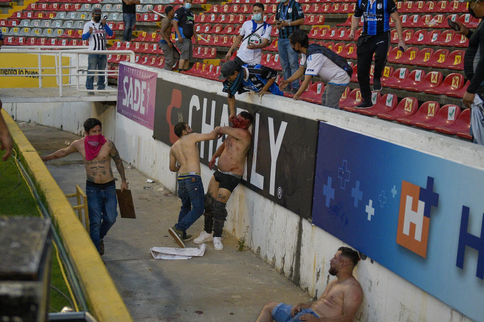 Fans clash during a Mexican soccer league match between the host Queretaro and Atlas from Guadalajara, at the Corregidora stadium, in Queretaro, Mexico, Saturday, March 5, 2022. Multiple people were injured during the brawl, including two critically. (AP Photo/Sergio Gonzalez)