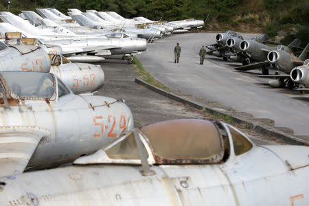 Albanian Air Force members walk near dozens of MIG-s jet fighters in Kucova Air Base in Kucova, Albania, October 3, 2018. REUTERS/Florion Goga