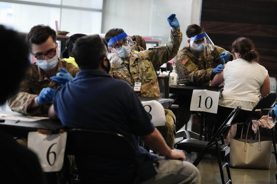 FILE - In this March 25, 2021, file photo, U.S. Department of Defense members administer vaccines to people at Mercedes-Benz Stadium in Atlanta. A new poll from The Associated Press-NORC Center for Public Affairs Research shows that the percentage of Americans resisting getting inoculated has shrunk in the past few months. But it’s still not enough to pull America out of the pandemic, and reach herd immunity. (AP Photo/Brynn Anderson, File)