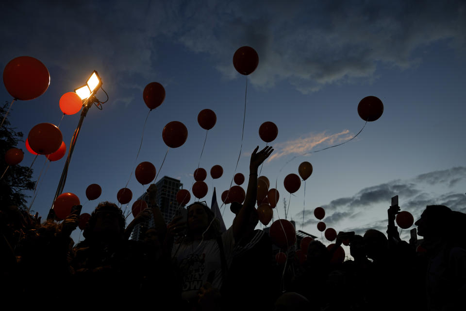 Israeli protesters release balloons as they call for the release of the Bibas family, whose members are being held hostage in the Gaza Strip by the Hamas militant group, in Tel Aviv, Tuesday, Nov. 28, 2023. (AP Photo/Ariel Schalit)