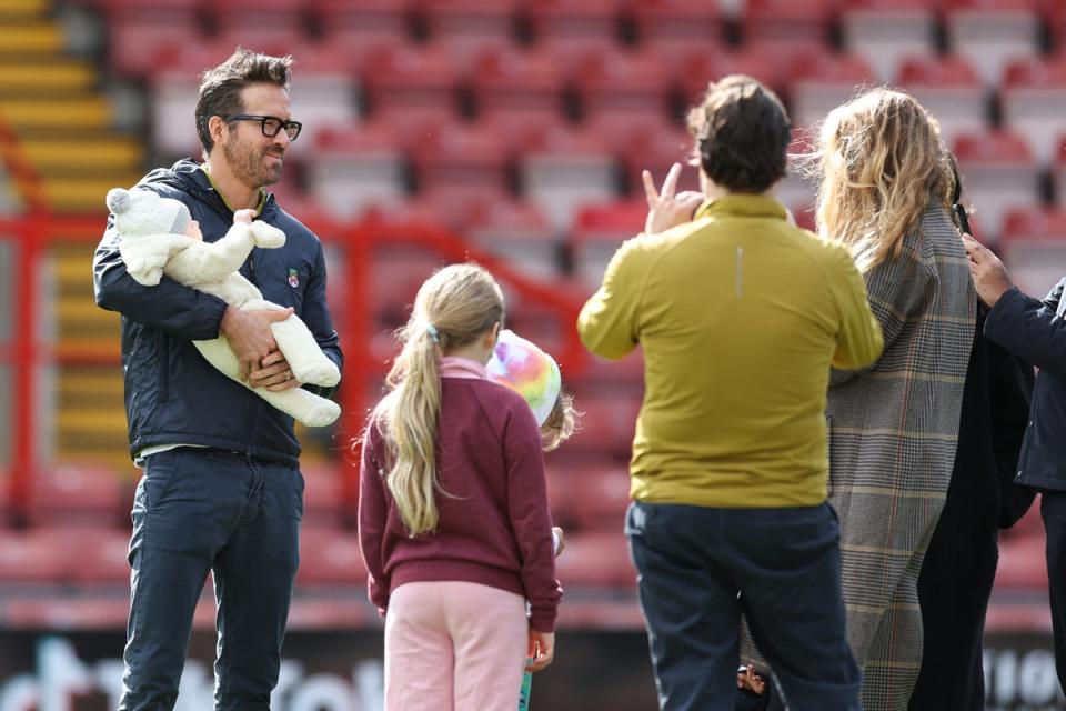Wrexham co-owner Ryan Reynolds has pictures of himself with his children on the pitch at The Racecourse Ground, Wrexham prior to the Vanarama National League match between Wrexham and York City at the Racecourse Ground on March 25, 2023 in Wrexham (Getty)