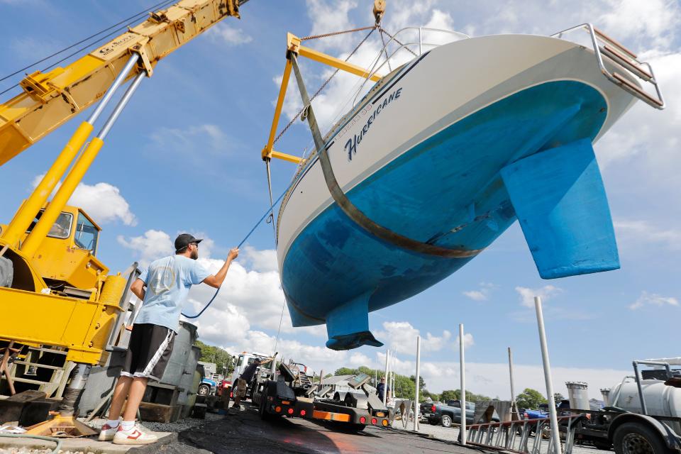 Chad Richard and fellow Davis & Tripp Marina and Boat Yard crews pull a sailboat named Hurricane from the waters of Padanaram harbor in Dartmouth in preparation for the arrival of hurricane Lee.