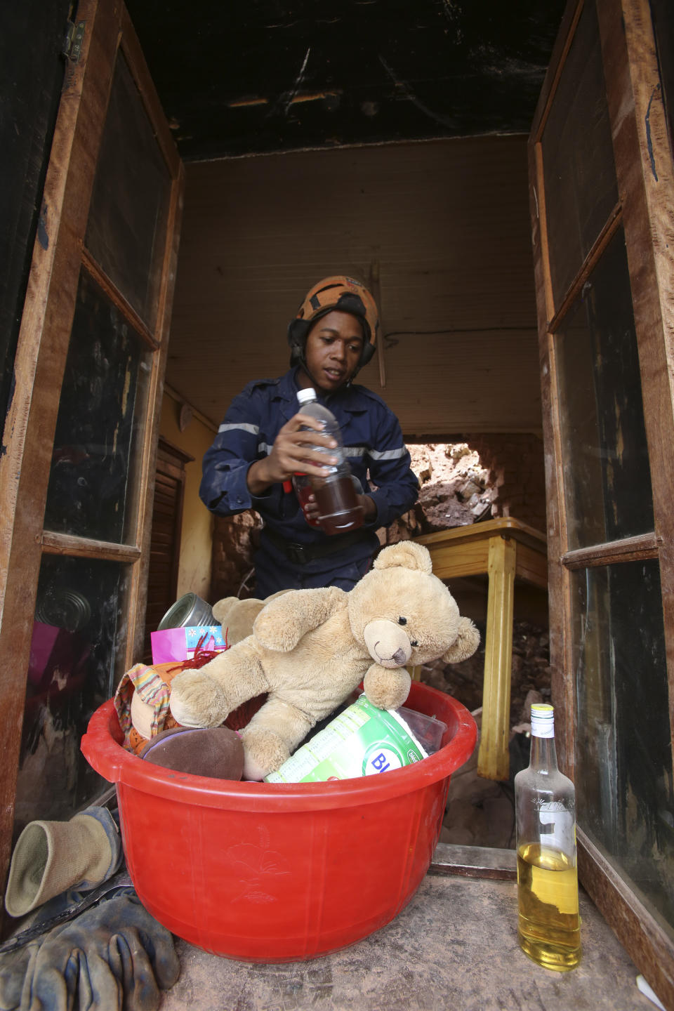 A fireman removes belongings from a home that was damaged by a landslide caused by tropical storm Ana in Antananarivo, Madagascar, Wednesday, Jan. 26, 2022. Six people died in the house. With heavy rains continuing, rivers in Antananarivo are rising and officials are urging residents to leave low-lying areas of the capital city and surrounding areas. (AP Photo/Alexander Joe)