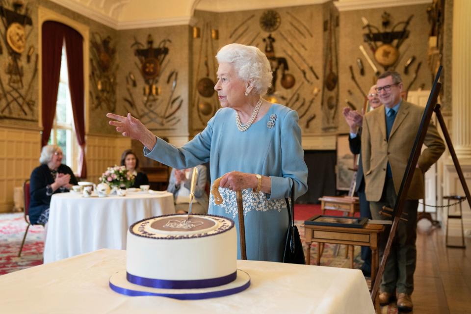 Queen Elizabeth II cuts a cake at a reception to mark the start of her Platinum Jubilee at Sandringham House in Norfolk, where she hosted members of the local community and charities on Feb. 5, 2022, the eve of Accession Day, the 70th anniversary of her reign.