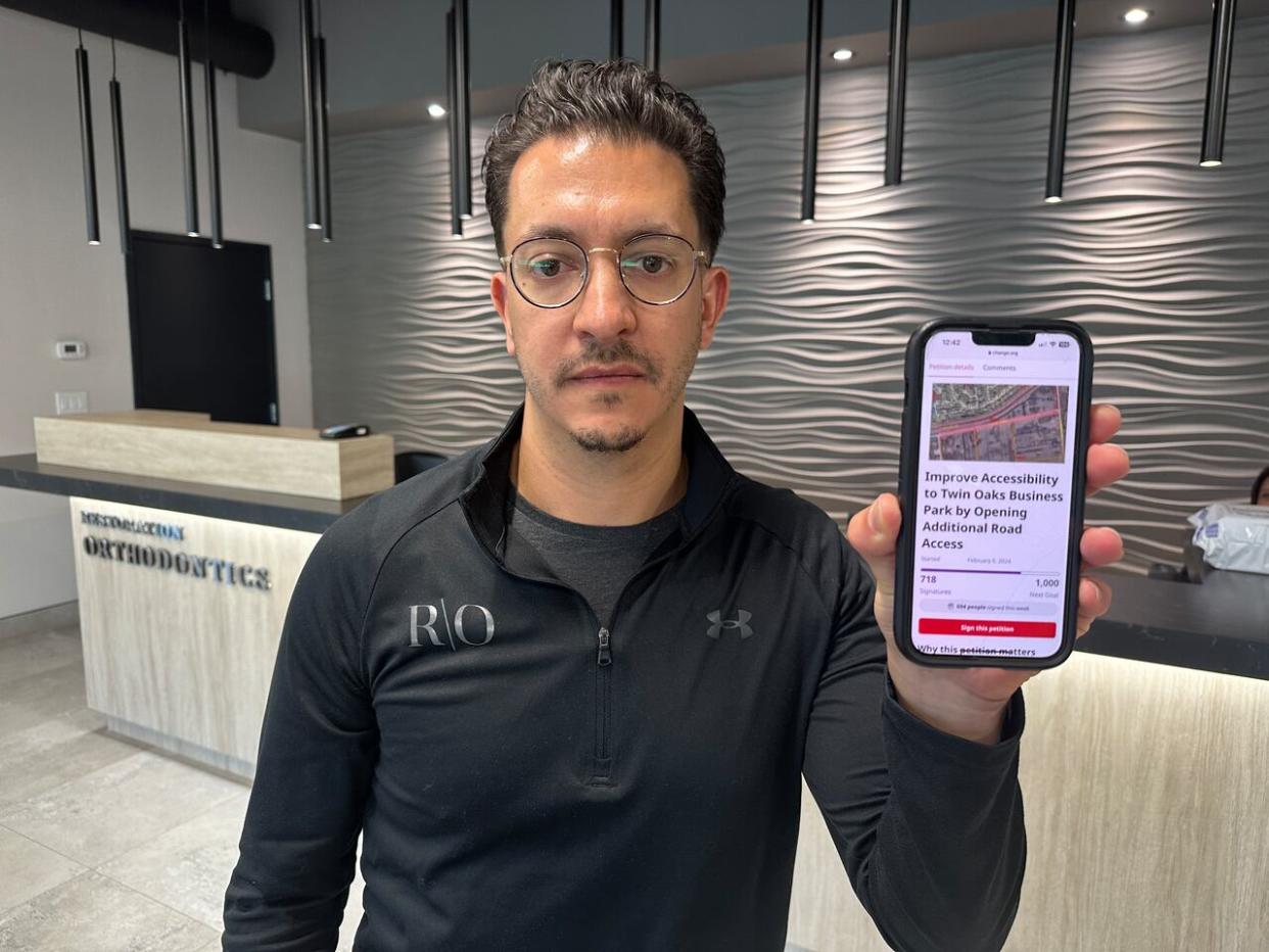 Orthodontist Mark Parete holds up his online petition calling for a new access road for the Twin Oaks Business Park. (Dale Molnar/CBC - image credit)