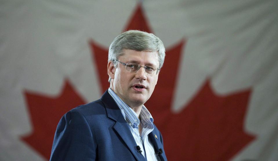 Harper parle avec un drapeau canadien derrière lui