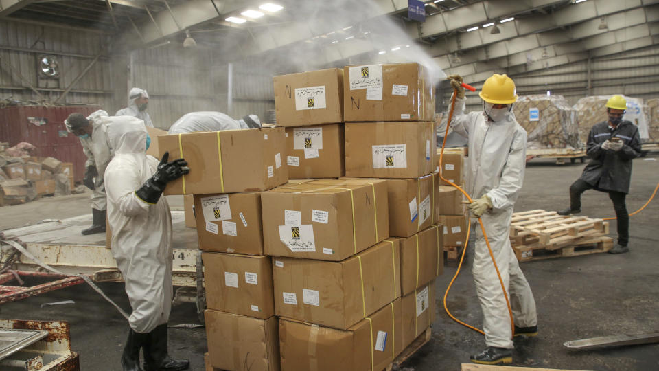 In this Wednesday, June 17, 2020, workers disinfect boxes of medical supplies on arrival at Sanaa International Airport in Sanaa, Yemen. The shipment includes ventilators, coronavirus test kits, PCR machines and personal protective equipment. Organized by the United Nations and private companies, it comes as the UN is facing a funding shortage for its operations in the war-torn country, where officials and medical experts fear the coronavirus could be spreading unchecked due to limited medical facilities. (World Health Organization via AP)