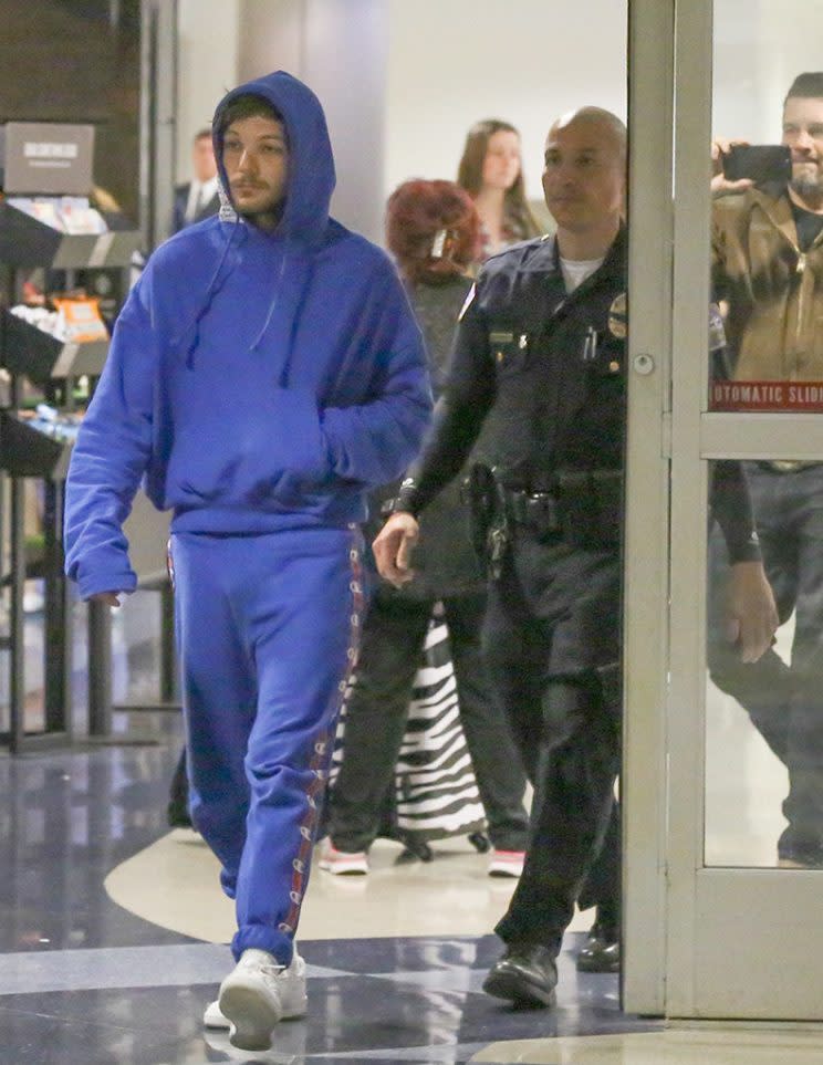 Louis Tomlinson is escorted by police at LAX.