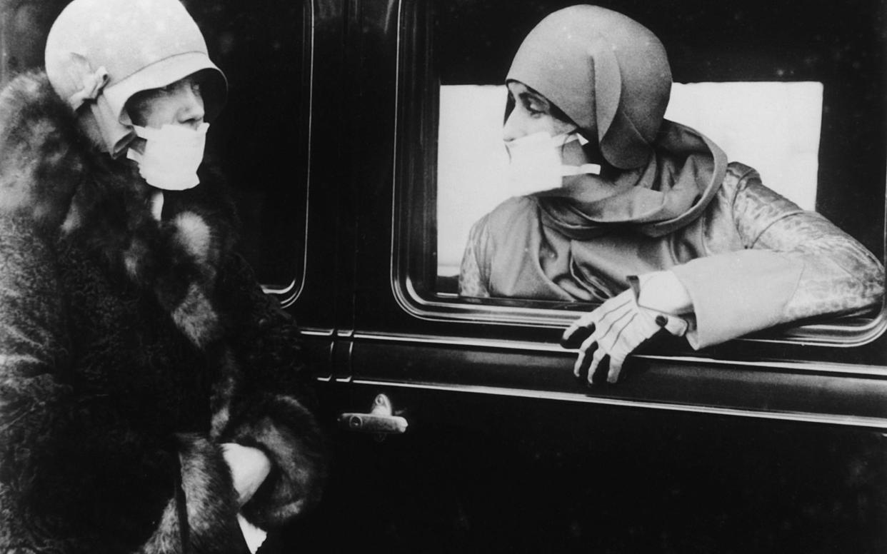 Two women wearing masks during a flu epidemic in 1929 - Getty